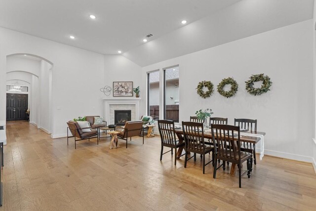 113 University Lands Dr, Liberty Hill, TX 78642 - dining space with arched walkways, light wood finished floors, a glass covered fireplace, recessed lighting, and baseboards