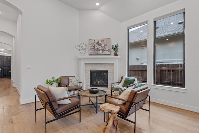 113 University Lands Dr, Liberty Hill, TX 78642 - sitting room featuring arched walkways, baseboards, a stone fireplace, light wood-type flooring, and high vaulted ceiling
