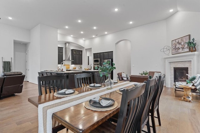 113 University Lands Dr, Liberty Hill, TX 78642 - dining space with arched walkways, light wood-style flooring, a stone fireplace, and recessed lighting