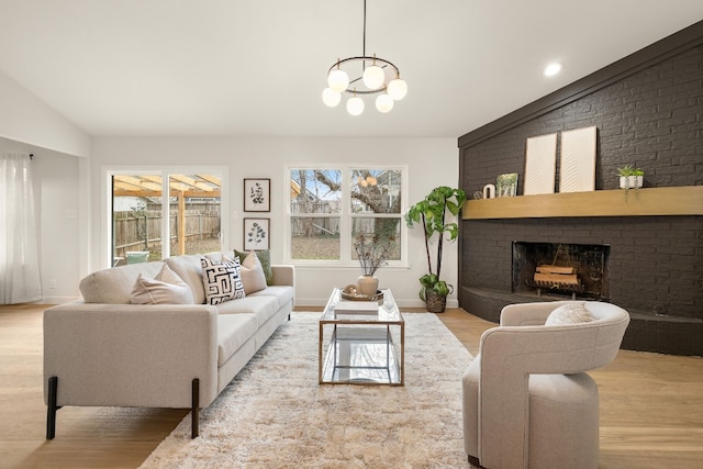 living room featuring lofted ceiling, a brick fireplace, and light hardwood / wood-style flooring