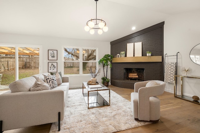 living room featuring lofted ceiling, a chandelier, hardwood / wood-style floors, and a fireplace