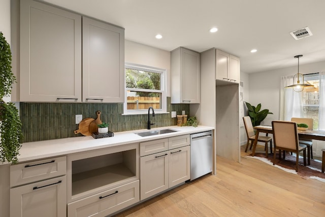 kitchen with sink, gray cabinetry, dishwasher, light hardwood / wood-style floors, and decorative backsplash