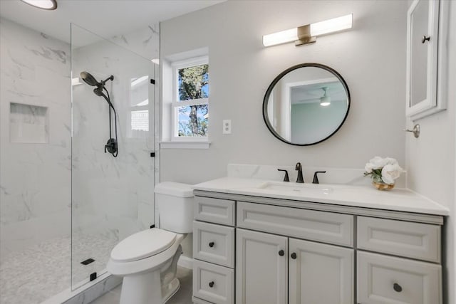 bathroom featuring vanity, a tile shower, and toilet