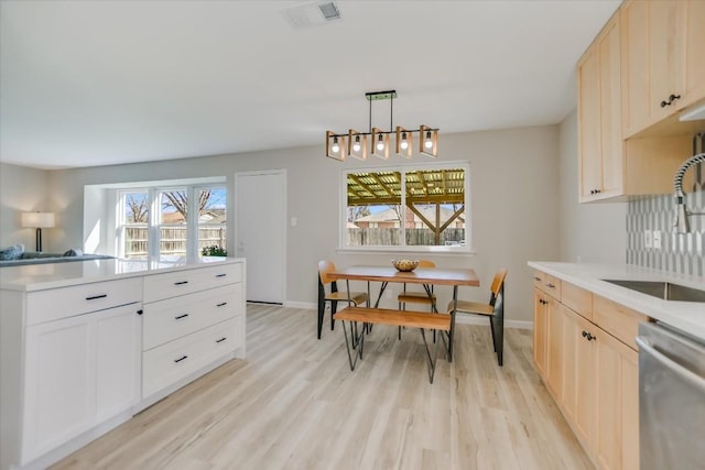 kitchen with sink, decorative light fixtures, light hardwood / wood-style floors, and dishwasher