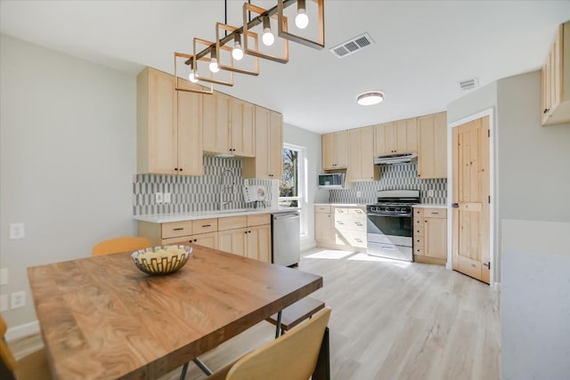 kitchen featuring stainless steel appliances, light brown cabinetry, and decorative backsplash