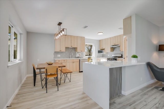 kitchen featuring hanging light fixtures, backsplash, stainless steel range, light brown cabinetry, and kitchen peninsula