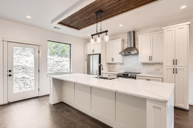 22300 Shotts Dr, Spicewood, TX 78669 - kitchen featuring wall chimney exhaust hood, stainless steel appliances, a sink, dark wood finished floors, and an island with sink