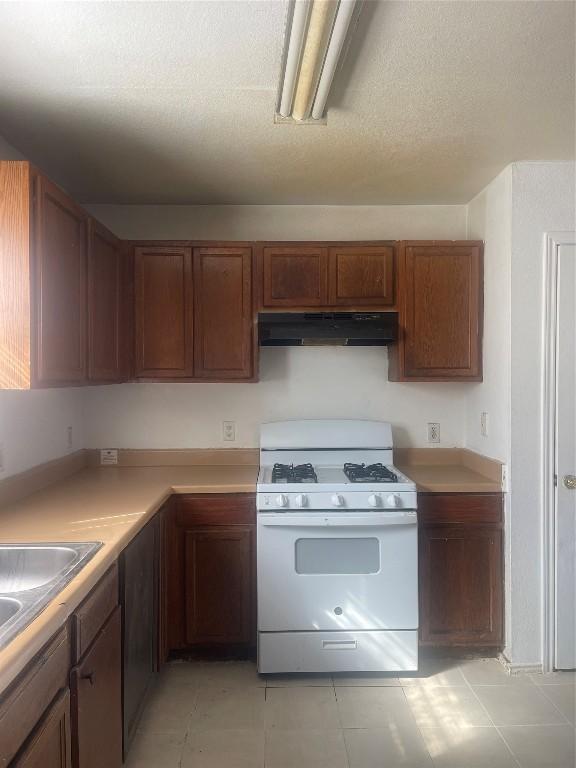 kitchen featuring sink, white gas stove, and a textured ceiling