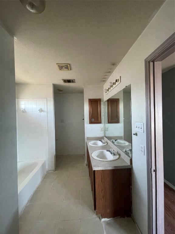 bathroom with tile patterned floors, vanity, and a bath