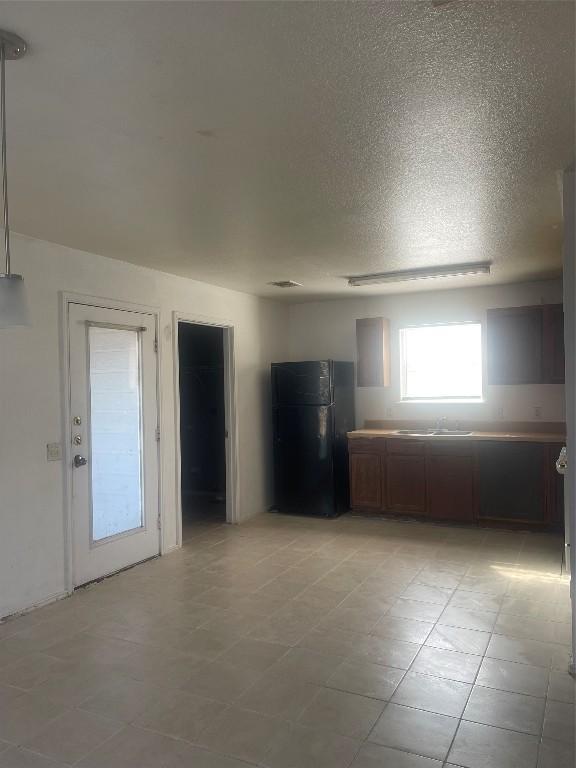 kitchen featuring black fridge and a textured ceiling