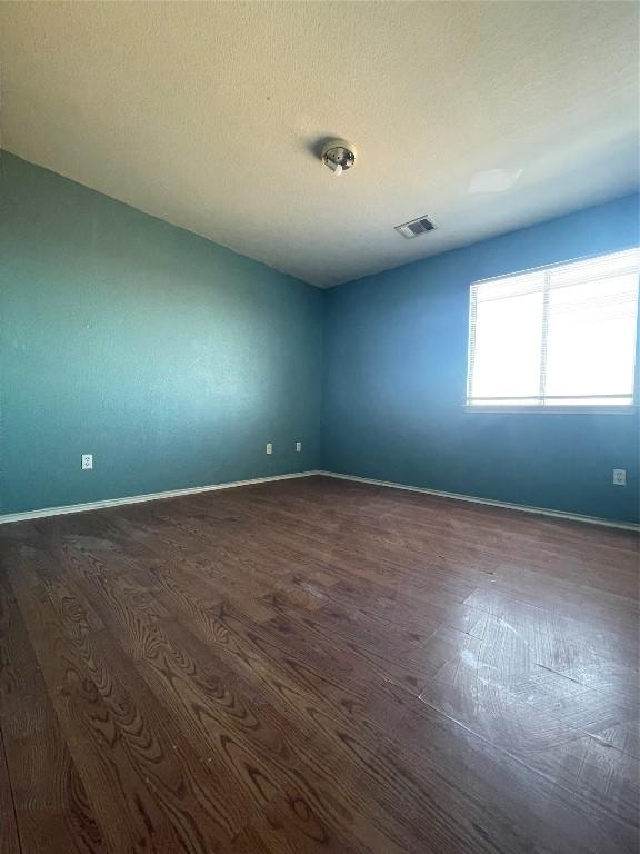 unfurnished room featuring dark hardwood / wood-style flooring and a textured ceiling