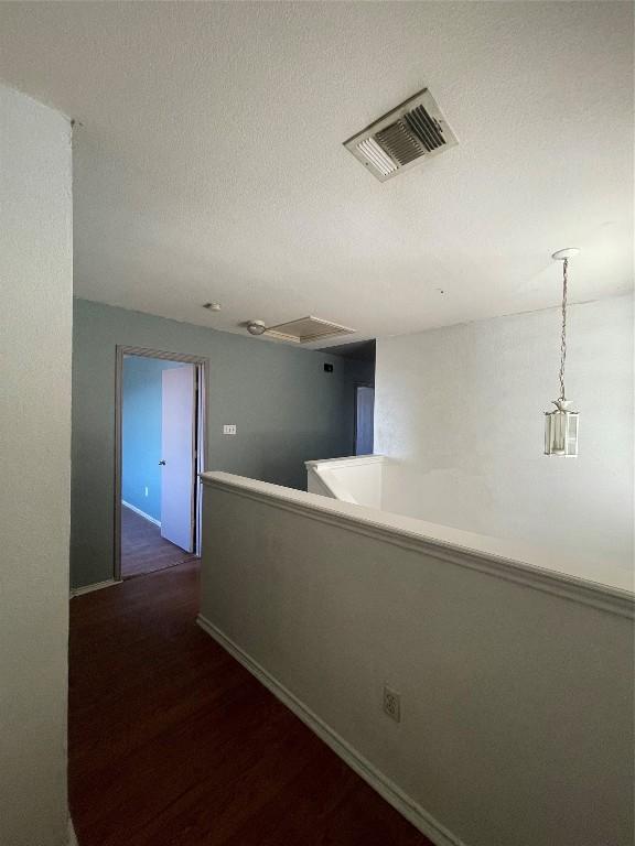 hallway with dark wood-type flooring and a textured ceiling