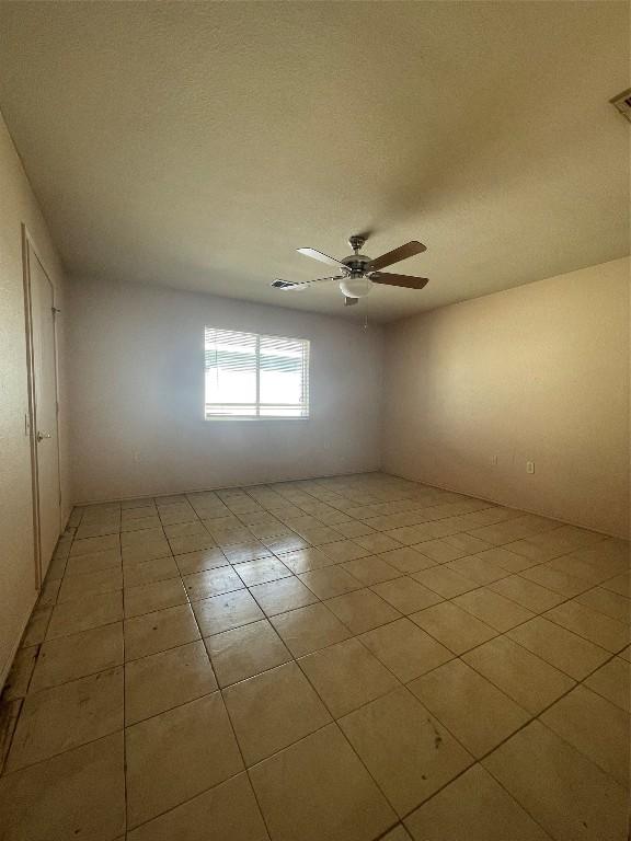 spare room featuring light tile patterned flooring, ceiling fan, and a textured ceiling