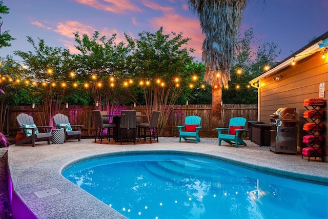 pool at dusk featuring a patio