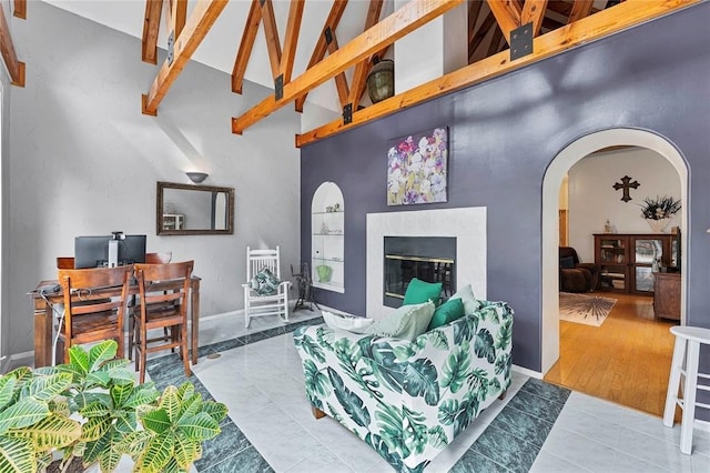 tiled living room with beam ceiling, a premium fireplace, and high vaulted ceiling