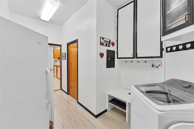 clothes washing area with cabinets, washer / clothes dryer, electric panel, and light hardwood / wood-style flooring