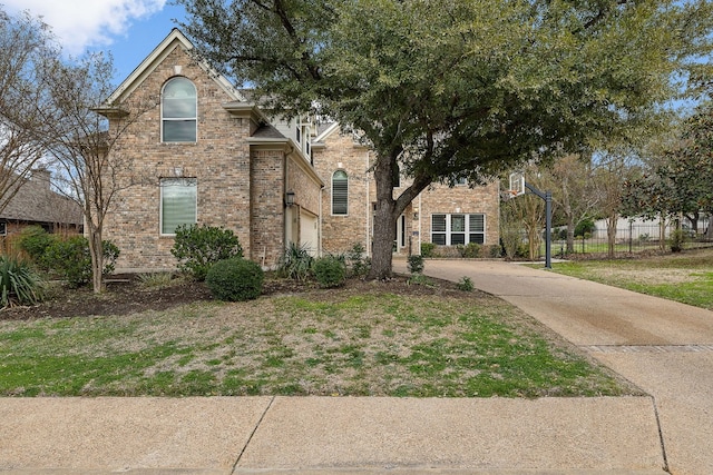 view of front facade with concrete driveway, fence, and brick siding