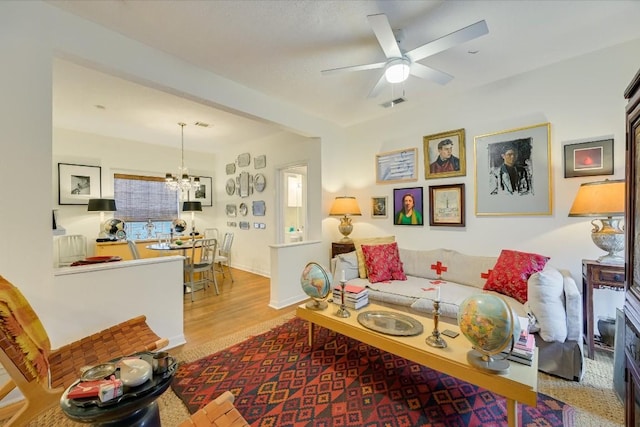 living room with hardwood / wood-style flooring and ceiling fan with notable chandelier