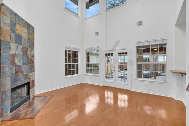 unfurnished living room featuring hardwood / wood-style flooring, a tile fireplace, and french doors