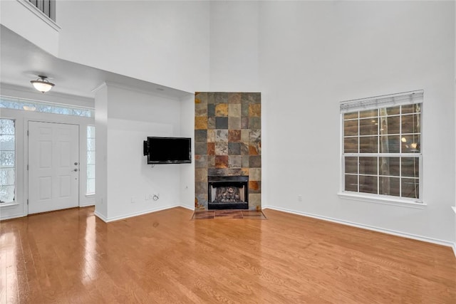 unfurnished living room with hardwood / wood-style floors, a towering ceiling, and a fireplace