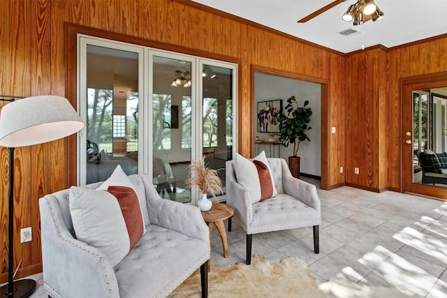 interior space with ceiling fan, ornamental molding, and wooden walls