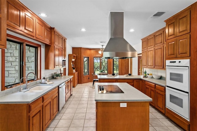 kitchen with sink, light tile patterned floors, appliances with stainless steel finishes, kitchen peninsula, and island exhaust hood