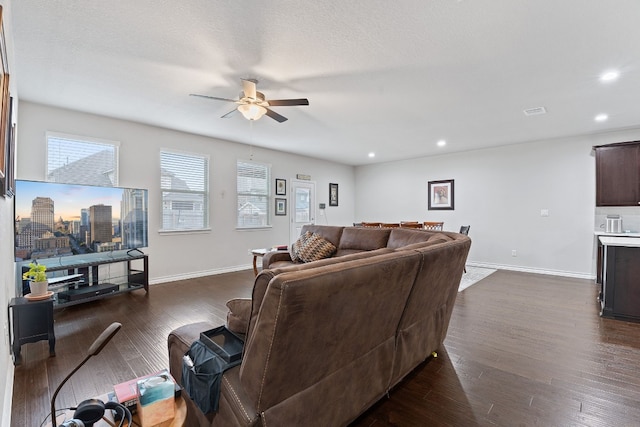 living room with ceiling fan, a textured ceiling, and dark hardwood / wood-style flooring