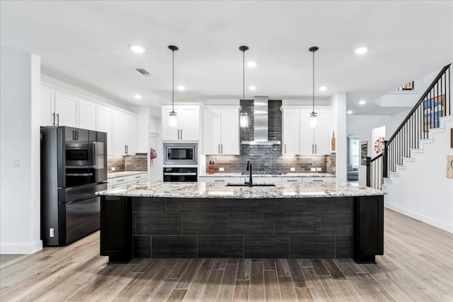 312 Olinda Way, Liberty Hill, TX 78642 - kitchen featuring a spacious island, a sink, stainless steel appliances, wall chimney range hood, and white cabinets