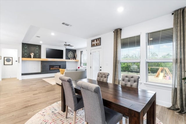 312 Olinda Way, Liberty Hill, TX 78642 - dining area featuring a ceiling fan, a glass covered fireplace, light wood-style flooring, baseboards, and visible vents