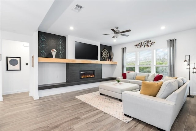 312 Olinda Way, Liberty Hill, TX 78642 - living area with wood finished floors, a glass covered fireplace, ceiling fan, and visible vents