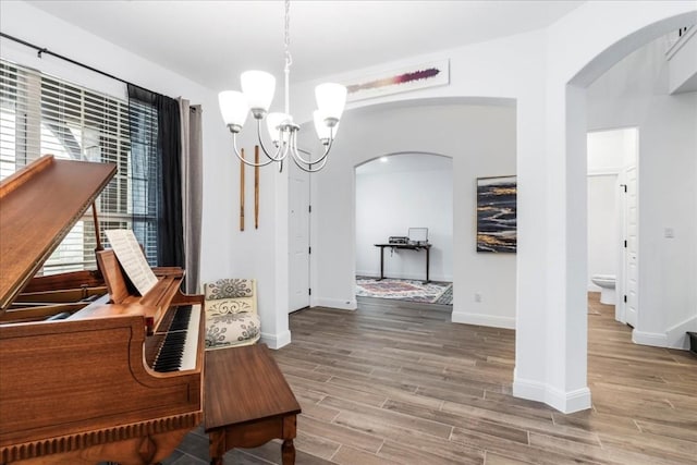 312 Olinda Way, Liberty Hill, TX 78642 - hallway with arched walkways, baseboards, a chandelier, and light wood finished floors