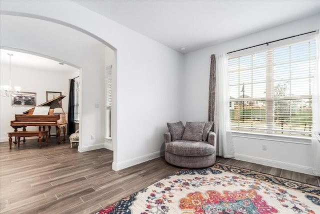 312 Olinda Way, Liberty Hill, TX 78642 - sitting room with arched walkways, baseboards, wood finished floors, and a notable chandelier