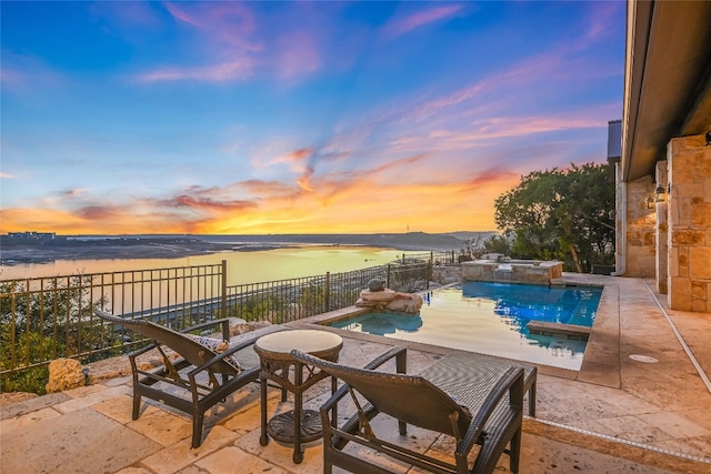 pool at dusk with a water view and a patio