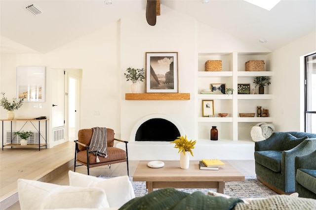 sitting room featuring lofted ceiling, built in shelves, and light wood-type flooring