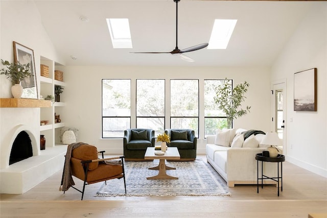 living room featuring lofted ceiling with skylight, ceiling fan, and light wood-type flooring