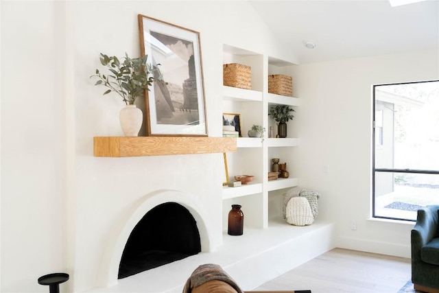 living area featuring lofted ceiling, built in features, and light hardwood / wood-style floors