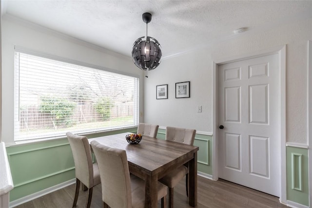 dining area with wood-type flooring, ornamental molding, a notable chandelier, and a textured ceiling