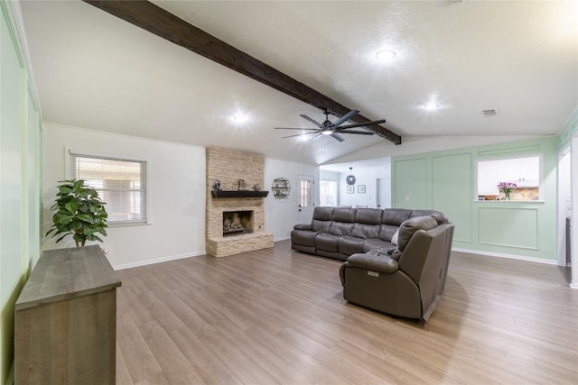 living room with plenty of natural light, vaulted ceiling with beams, a fireplace, and light hardwood / wood-style flooring