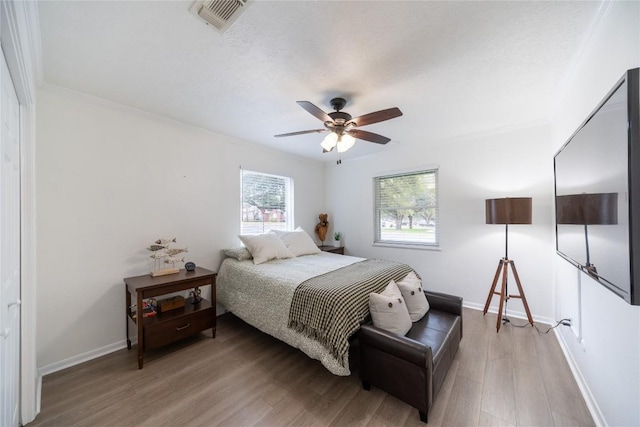 bedroom featuring hardwood / wood-style flooring, ornamental molding, and ceiling fan