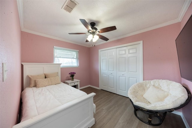 bedroom featuring a closet, ornamental molding, ceiling fan, and light hardwood / wood-style flooring