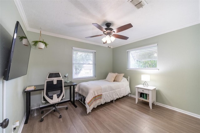 bedroom with hardwood / wood-style flooring, ornamental molding, a textured ceiling, and ceiling fan