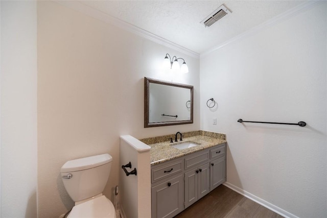 bathroom featuring crown molding, hardwood / wood-style flooring, vanity, a textured ceiling, and toilet