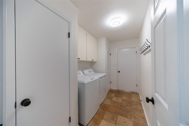 clothes washing area featuring separate washer and dryer, cabinets, and a textured ceiling