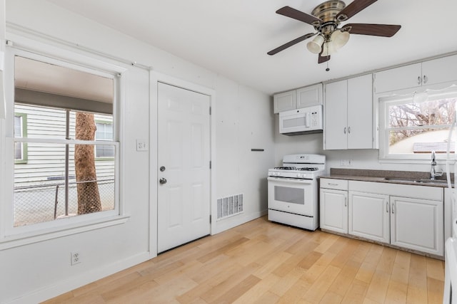 kitchen with sink, white cabinets, white appliances, and light hardwood / wood-style floors