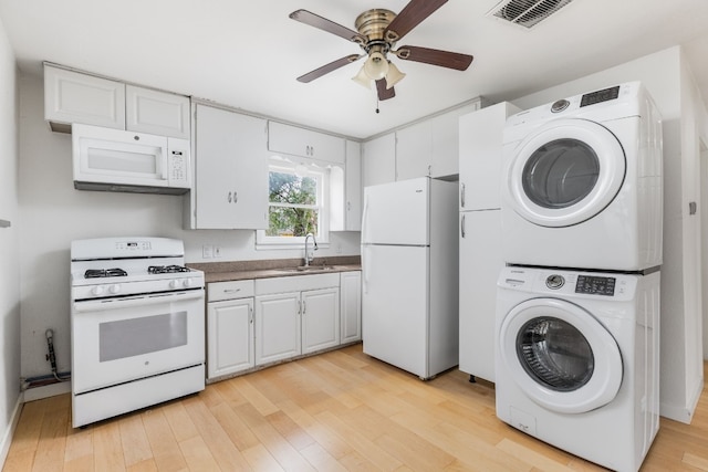 kitchen featuring stacked washer and dryer, white appliances, sink, and white cabinets