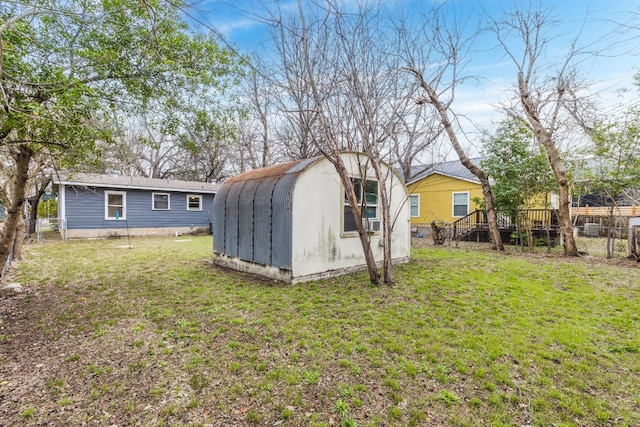 rear view of house with a wooden deck, an outdoor structure, and a lawn