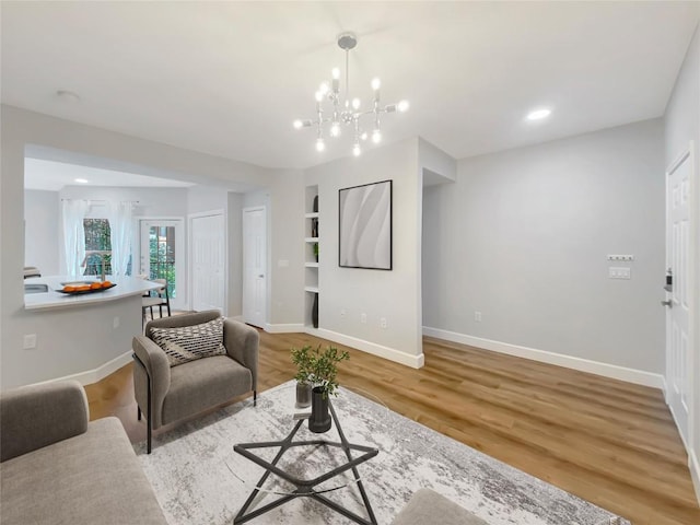 living room with an inviting chandelier, wood-type flooring, and built in features