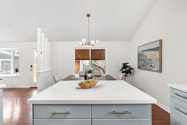 kitchen with gray cabinetry, a center island, dark hardwood / wood-style flooring, a notable chandelier, and pendant lighting