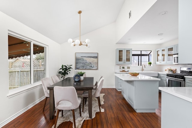 dining area featuring sink, a notable chandelier, vaulted ceiling, and dark hardwood / wood-style floors