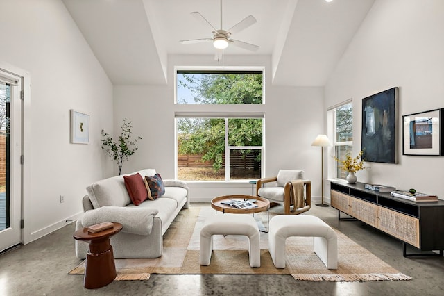 living area with baseboards, concrete floors, and high vaulted ceiling